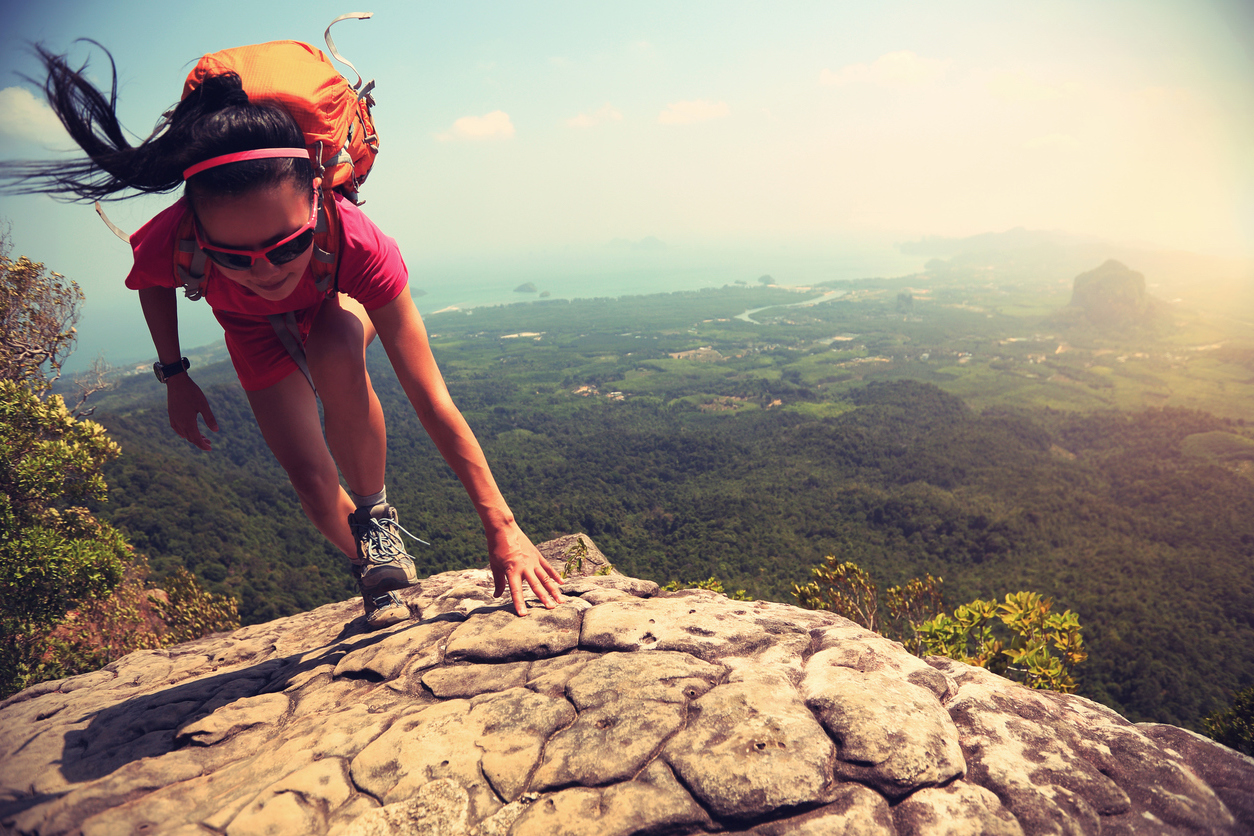 young asian woman hiker climbing rock on mountain peak cliff - Savvy Tokyo