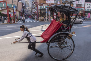 A rickshaw driver pulling tourists around Asakusa.
