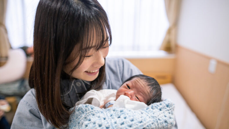 Young mother holding her new born baby in hospital - Savvy Tokyo